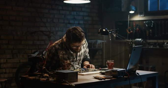 Slow motion shot of a man repairing a mother board in a garage