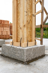 Brick house construction concept. Close up vertical photo of building support element with wooden column and concrete formwork against red brick wall