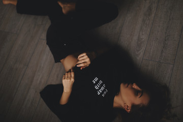 Attractive sexy woman lies on the floor. She looks sensuality. Hot girl wears total black look.