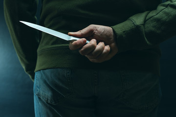 Criminal with knife weapon hidden behind his back