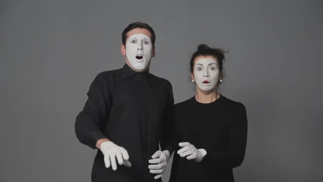 Scared mime artists man and woman on grey background.