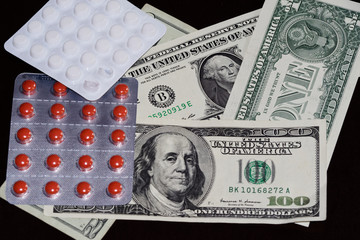 Pills in blister packaging and american dollars on black background