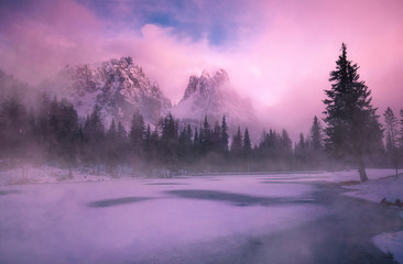 Mystic sunset at Lago Antorno in the Dolomites with fog and clouds