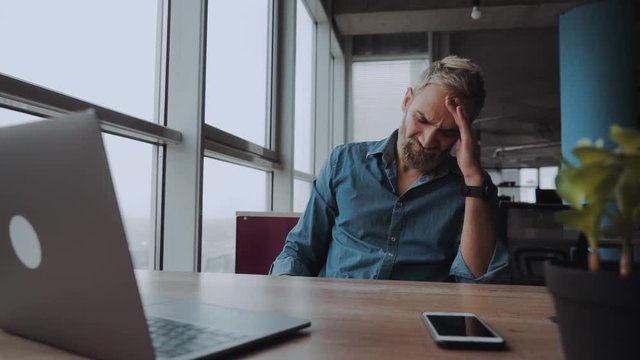 Overworked minded man having headache after working day