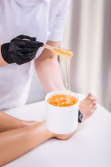 Professional depilation master removing unwanted hair from legs