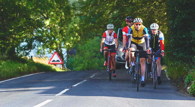 A group of cyclists on a bike race on a sunny day along country roads in the UK. - Powered by Adobe