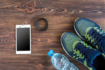 Fitness tracker, smart phone and sneakers on wooden table with copy space. Healthy lifestyle background. 