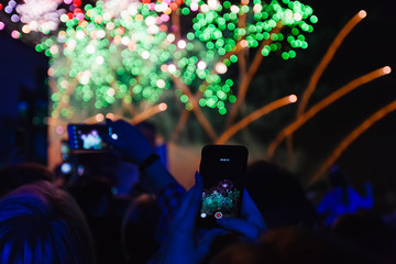 People in the crowd are recording fireworks on their phones.