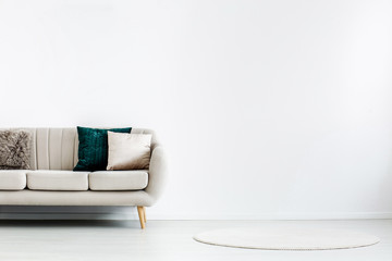 Empty white wall with copy space behind beige couch with pillows