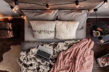 Top view of comfortable king size bed with cozy bedding, warm blankets and laptop