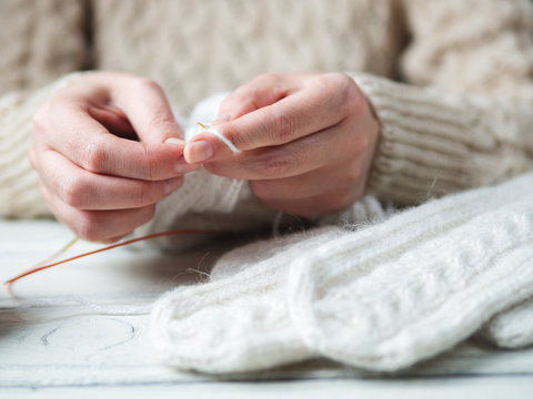 Woman knits winter warm clothes closeup