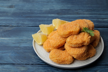 chicken nuggets on a plate with lemon slices on a blue wooden table