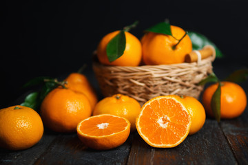 Tangerines in a wooden basket on a dark wooden table