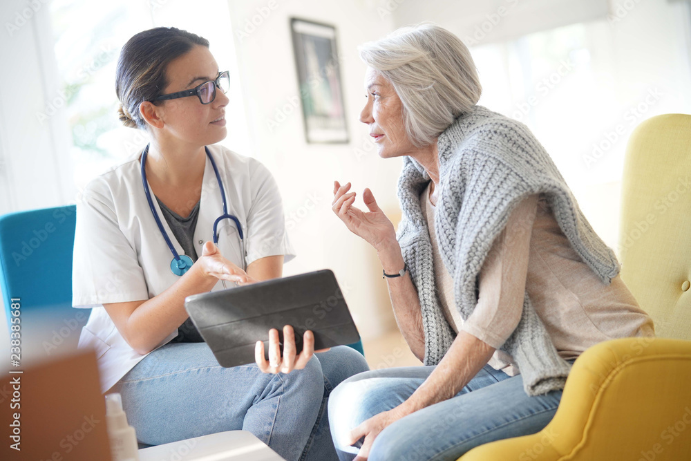 Wall mural doctor going through results and medication on tablet with senior patient