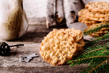 Havreflarn - scandinavian crispy slim oatmeal cookies, fir and birch branches and bark on old wooden background. Fast and easy scandinavian pastry. Cozy winter treat. Hygge. Fika. Christmas