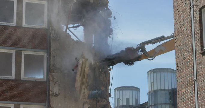 Demolition crane tearing old building apart in slow-motion