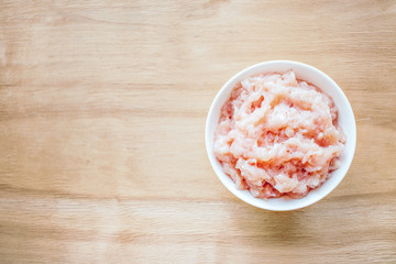 Chicken meat recall. Food Safety. Raw chicken meat. Fresh minced meat in a round white plate on a wooden background. Dietary meat, low-calorie foods, an ingredient for chicken dishes