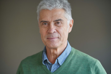 Portrait of modern smiling senior man on grey background