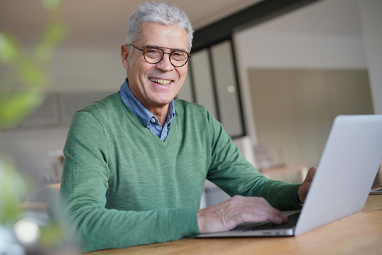  Modern senior man working on laptop at home