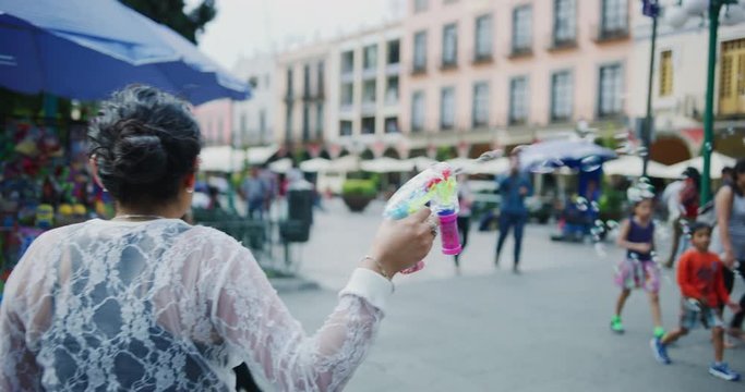 Saleswoman holding a bubble gun in Zocalo de Puebla area.