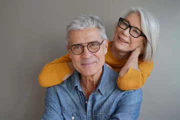 Foto op Plexiglas  Portrait of relaxed fun senior couple wearing glasses on background © goodluz