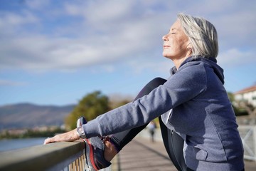  Flexible senior woman stretching outdoors after jog - obrazy, fototapety, plakaty