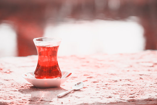 Hot turkish tea outdoors near water. Turkish tea and traditional turkish culture concept . Living coral theme - color of the year 2019