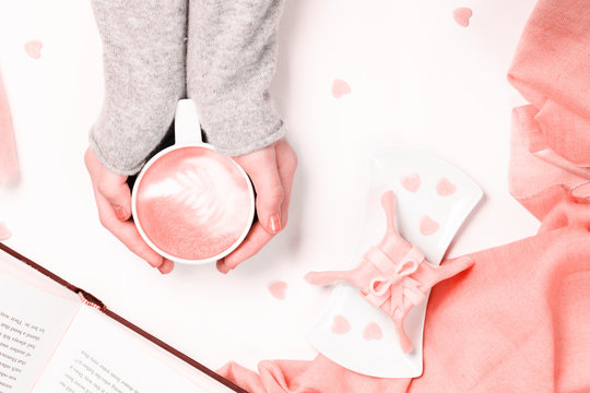 Female hands holding cup of cappuccino. Gift alike dessert with heart shape sprinkles. Flat lay. Valentines concept.  . Living coral theme - color of the year 2019
