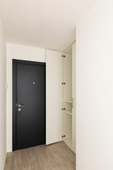 Black entrance door with open wardrobe