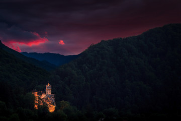 Bran Castle in spring, summer. One of the most famous landmarks in Romania, also known as Dracula's castle. Bran castle illuminated at night with a beautiful sunset in the background