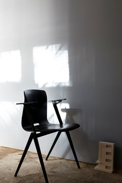 Schwarzer Bauhaus Stuhl neben Bauhaus Modell vor Licht Reflexen an Wand