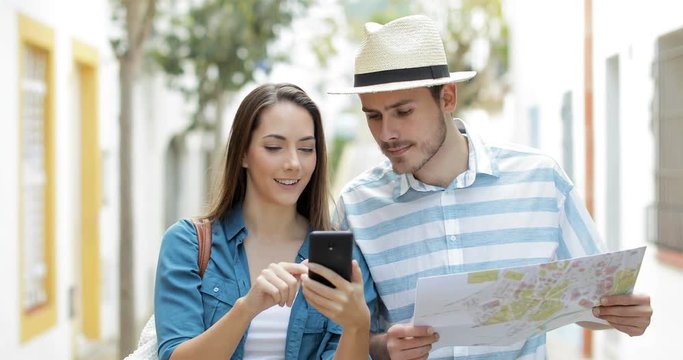 Happy couple of amazed tourists walking in the street of a town finding online bargain on vacation