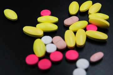 Assorted pharmaceutical medicine pills, tablets and capsules over yellow background