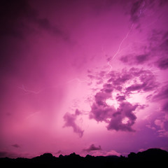 Lightning bolt striking at night with purple cloudy sky