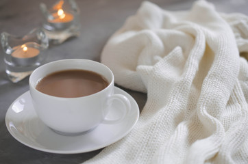Cup of cocoa on a table, candles and knited blanket.
