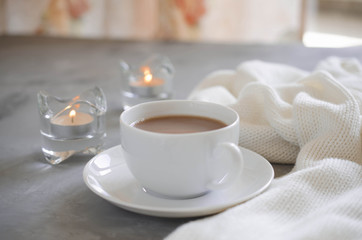 Cup of cocoa on a table, candles and knited blanket.