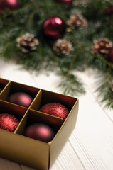 Christmas composition. Christmas burgundy toys on a white background. Behind a fir-tree with cones...