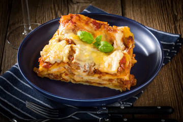 Piece of tasty hot lasagna with red wine.