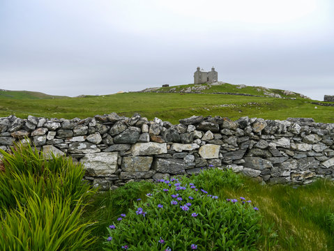 old drystone wall with abandoned house on a hill