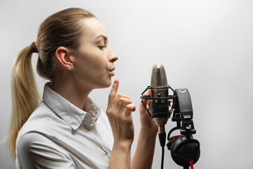 music, show business, people and voice concept - singer with headphones and microphone singing a...
