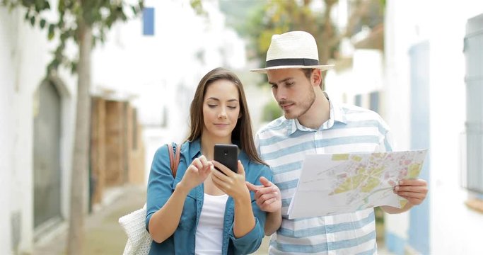 Couple of excited tourists walking in the street finding best online offer on a smart phone on vacation