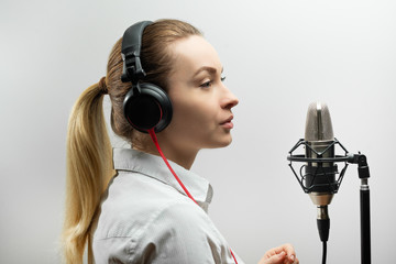 Female vocal recording. Young girl with microphone and headphones in recording studio. Recording of...