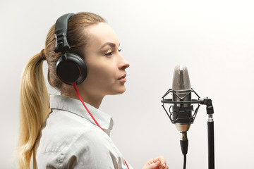 Female vocal recording. Young girl with microphone and headphones in recording studio. Recording of...