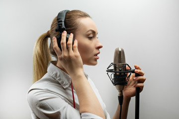 music, show business, people and voice concept - singer with headphones and microphone singing a...