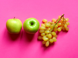 Above view of isolated set of a green apple with a bunch of sweet seedless grapes in studio with...