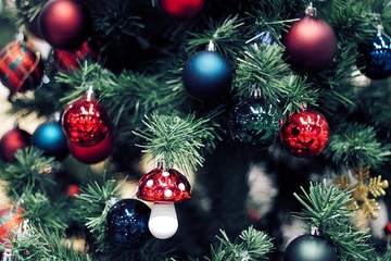 Closeup of red bauble hanging from a decorated Christmas tree. Happy new year concept