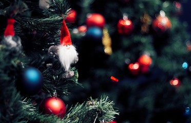 Closeup of red bauble hanging from a decorated Christmas tree. Happy new year concept