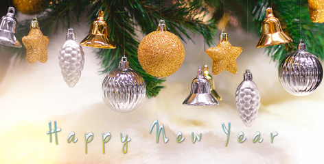 Shiny gold and silver christmas balls, stars and bells on white with pine tree for new year with happy new year text