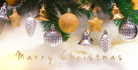 Shiny gold and silver christmas balls, stars and bells on white with pine tree for new year with marry christmas text