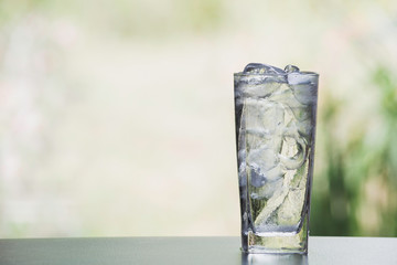 Ice cube and water in the glass on table with nature background